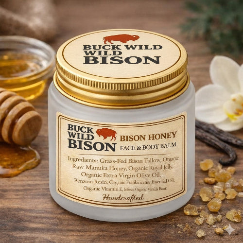 Buck Wild Bison honey balm jar on a wooden surface with honeycomb and flowers.